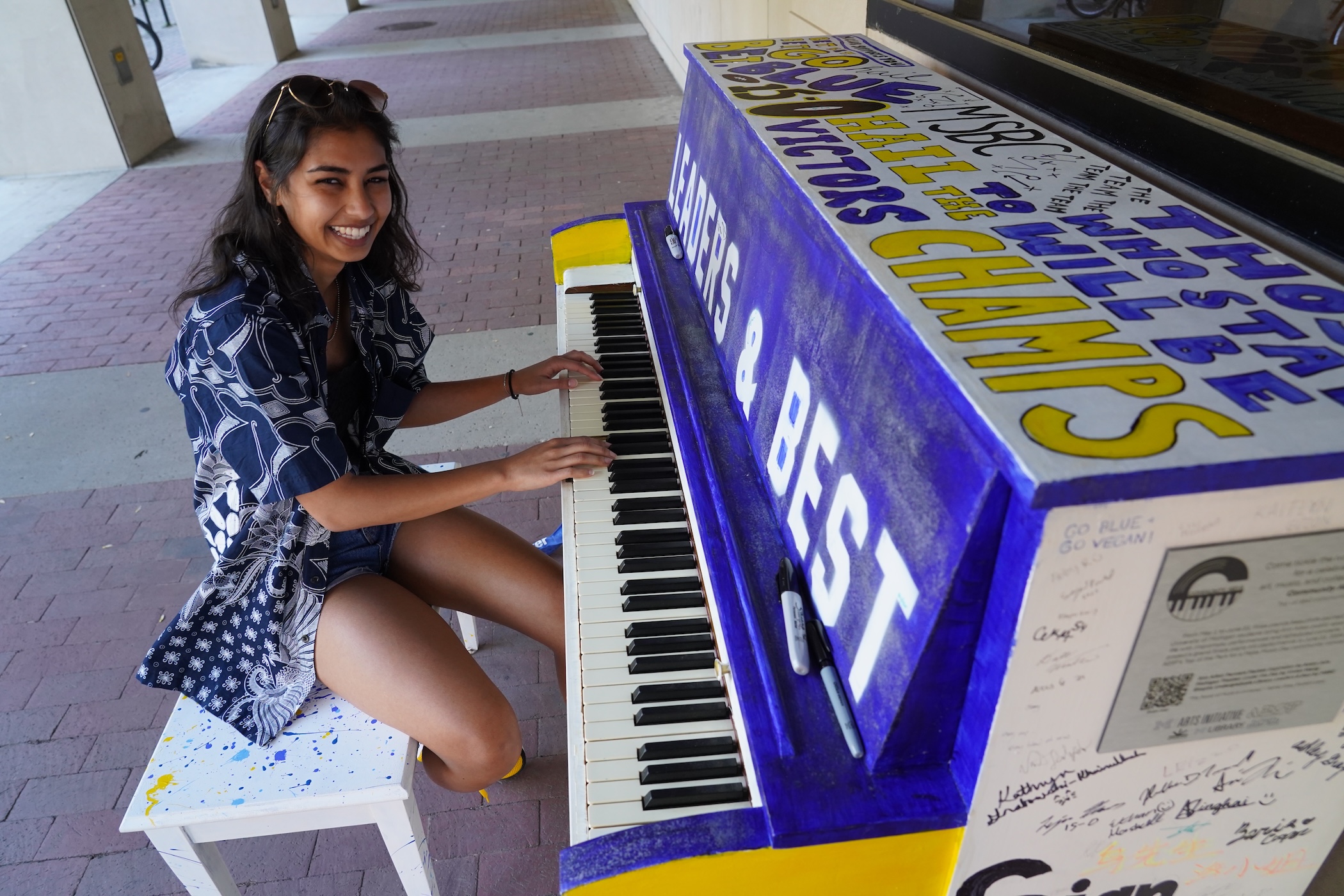 Navya Singhai grins as she plays the piano she helped paint.