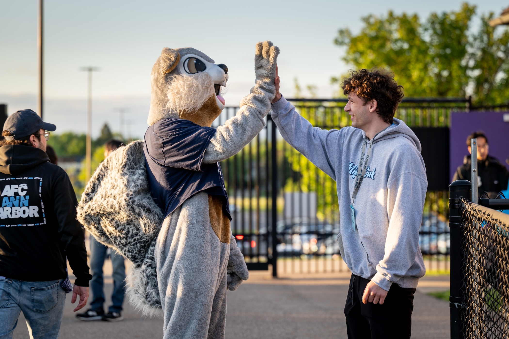 A sport management gives Nutmeg the squirrel, AFC Ann Arbor's team mascot, a high five.