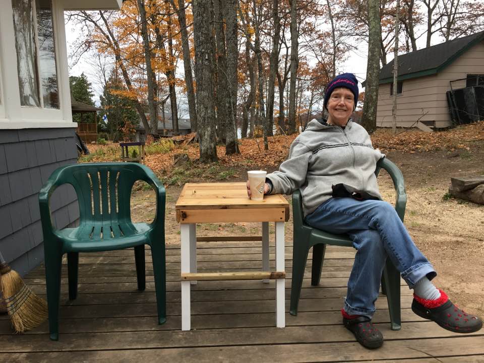 Aaron Saari's mother sitting in a chair outside on a porch with a cup of coffee