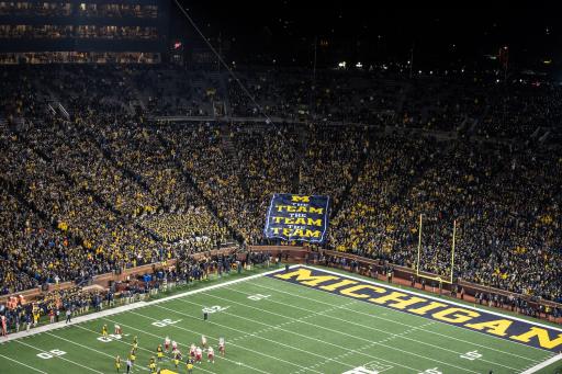 A University of Michigan game with flag reading &quot;The team the team the team&quot; in the crowd